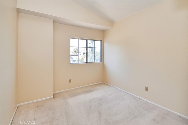 carpeted spare room with baseboards and lofted ceiling