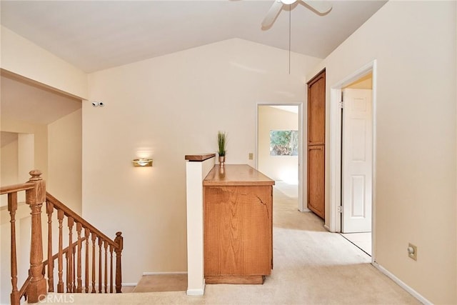 hall with baseboards, an upstairs landing, light carpet, and vaulted ceiling