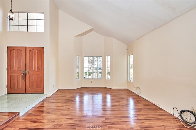 foyer entrance featuring baseboards, high vaulted ceiling, and wood finished floors