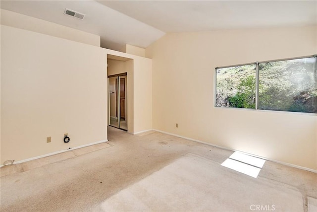 carpeted empty room with visible vents, baseboards, and vaulted ceiling