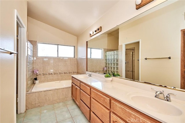 full bath with tile patterned flooring, lofted ceiling, a relaxing tiled tub, and a sink