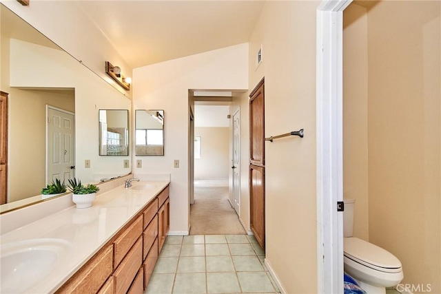 full bathroom featuring tile patterned floors, toilet, double vanity, and a sink