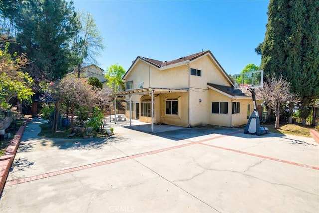 back of property with stucco siding, fence, driveway, and a patio area