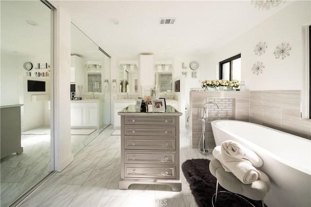 bathroom with visible vents, marble finish floor, a freestanding bath, and vanity