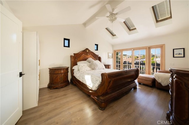 bedroom with vaulted ceiling with skylight, access to outside, wood finished floors, and ceiling fan