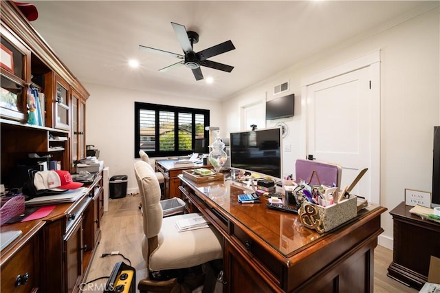 office area with baseboards, visible vents, light wood-style flooring, ornamental molding, and ceiling fan