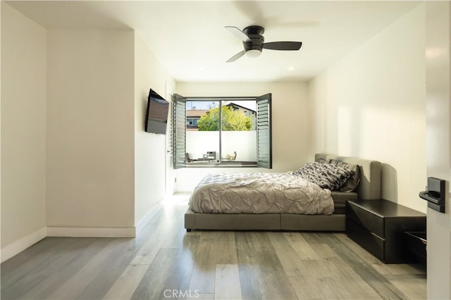 bedroom featuring light wood-style flooring, a ceiling fan, and baseboards