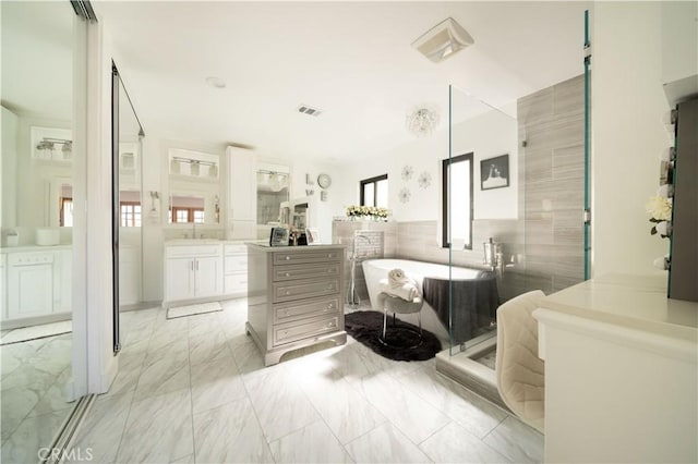 bathroom with marble finish floor, a stall shower, plenty of natural light, a freestanding bath, and vanity