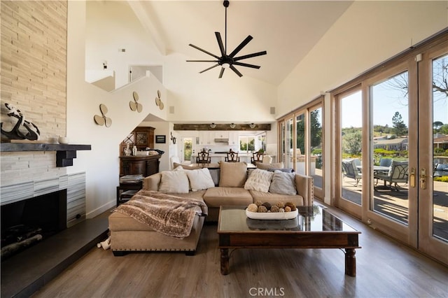 living room with a fireplace, ceiling fan, wood finished floors, and high vaulted ceiling