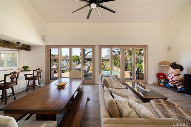 living room featuring french doors, a ceiling fan, a towering ceiling, and wood finished floors