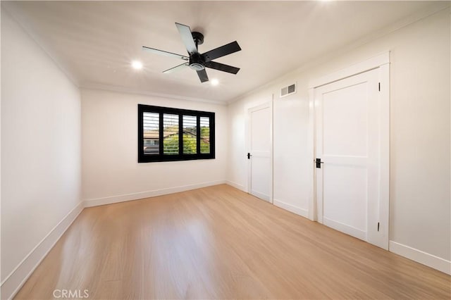 unfurnished bedroom with light wood finished floors, visible vents, crown molding, and baseboards