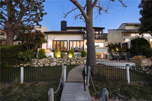 view of front of property with a fenced front yard, stucco siding, a chimney, and a patio