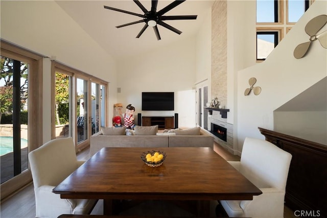 dining area featuring a fireplace, high vaulted ceiling, and ceiling fan