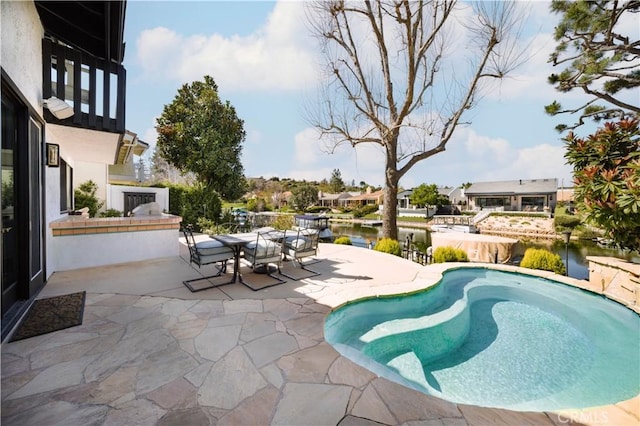 view of pool with outdoor dining space, a patio, and a water view