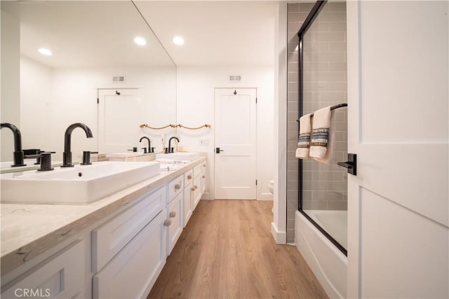 bathroom with double vanity, recessed lighting, wood finished floors, and a sink