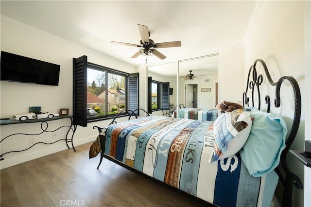 bedroom featuring a ceiling fan, crown molding, wood finished floors, and baseboards