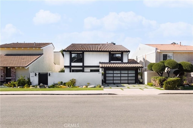 view of front of property featuring a fenced front yard, driveway, and a tiled roof