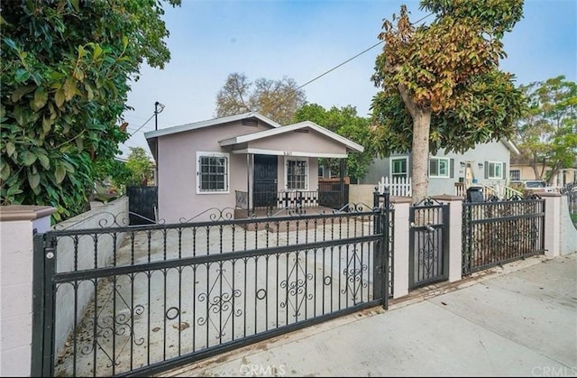 view of front facade featuring a gate, a fenced front yard, and stucco siding