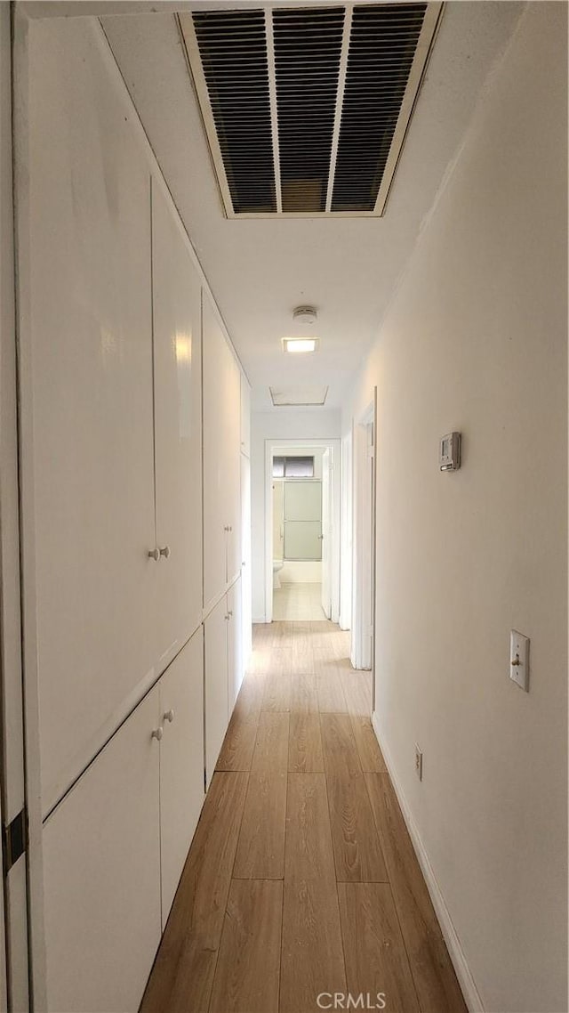 hall featuring visible vents, baseboards, and wood finished floors