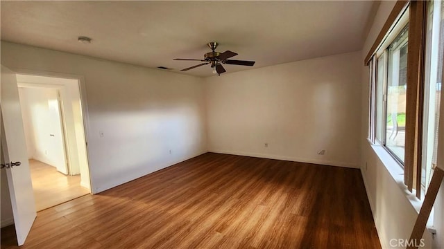 empty room with baseboards, wood finished floors, visible vents, and ceiling fan