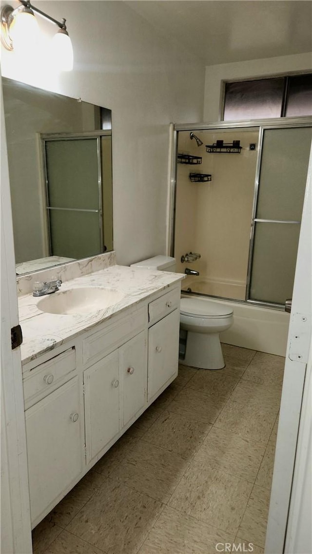 bathroom featuring combined bath / shower with glass door, toilet, and vanity