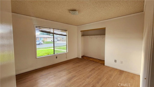 unfurnished bedroom featuring light wood finished floors, baseboards, a textured ceiling, and a closet