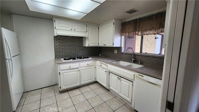 kitchen with decorative backsplash, light tile patterned flooring, white cabinets, white appliances, and a sink