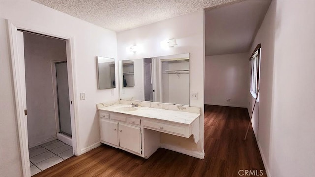 bathroom featuring vanity, wood finished floors, a stall shower, and a textured ceiling