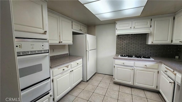 kitchen with ventilation hood, decorative backsplash, white appliances, and white cabinetry