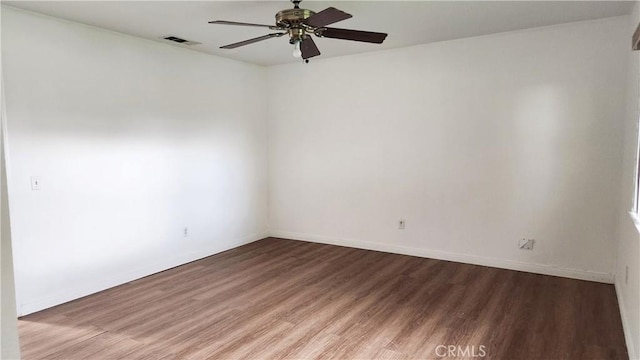 unfurnished room featuring a ceiling fan, wood finished floors, visible vents, and baseboards