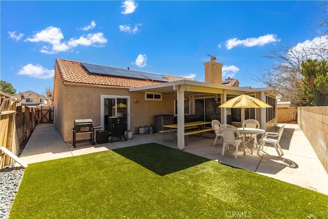 back of property featuring stucco siding, a patio, a fenced backyard, solar panels, and a tiled roof