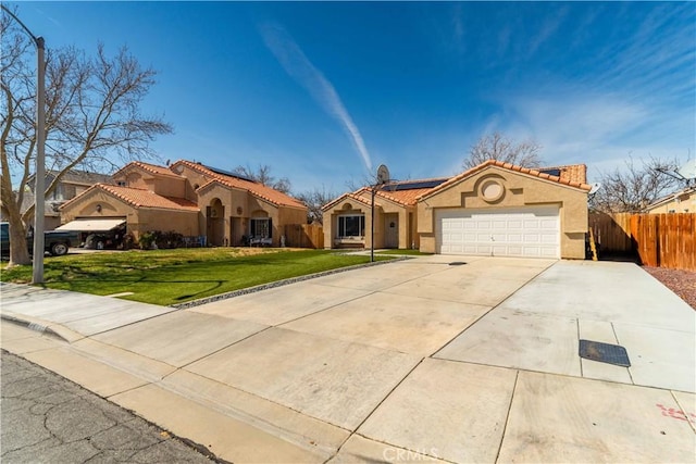 mediterranean / spanish home featuring fence, stucco siding, a front lawn, a garage, and roof mounted solar panels