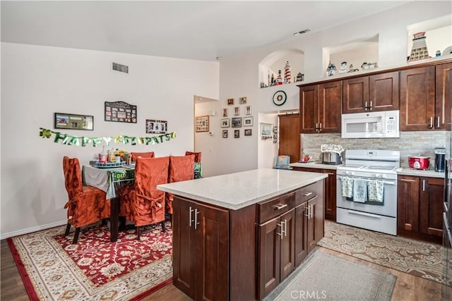 kitchen with visible vents, backsplash, white appliances, and light wood-type flooring