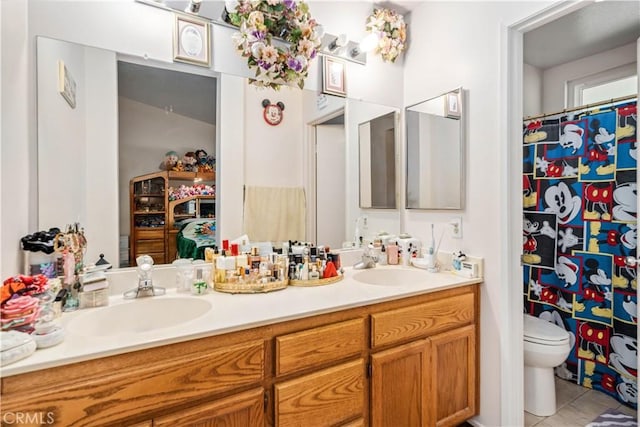 bathroom featuring a sink, toilet, double vanity, and tile patterned floors