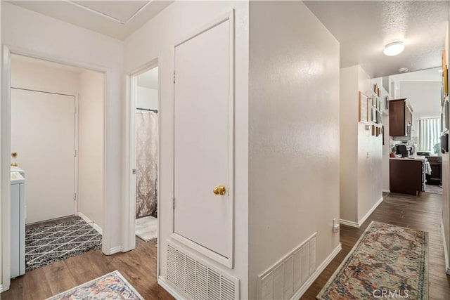 hallway featuring dark wood-style floors, visible vents, washer / dryer, and baseboards