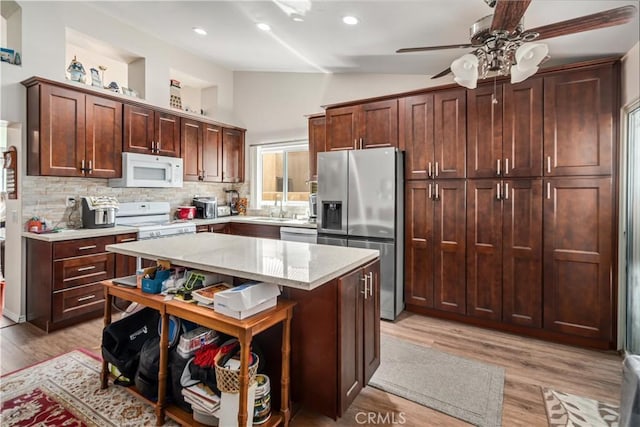 kitchen featuring light wood finished floors, appliances with stainless steel finishes, lofted ceiling, and a sink