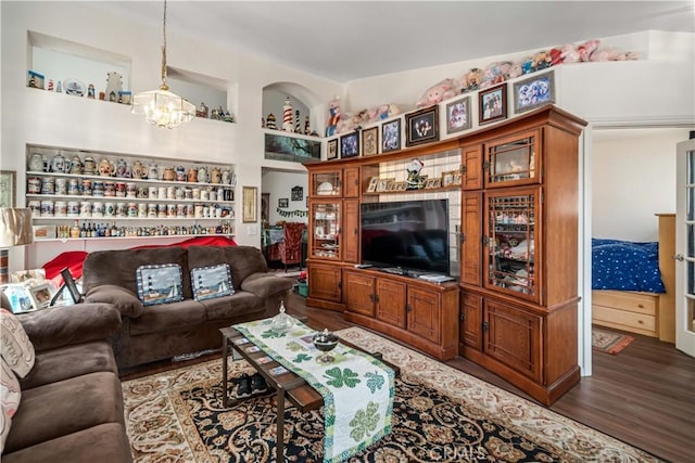 living room featuring a chandelier, vaulted ceiling, built in shelves, and wood finished floors