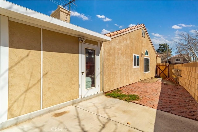 back of house featuring stucco siding, fence, a chimney, and a patio area