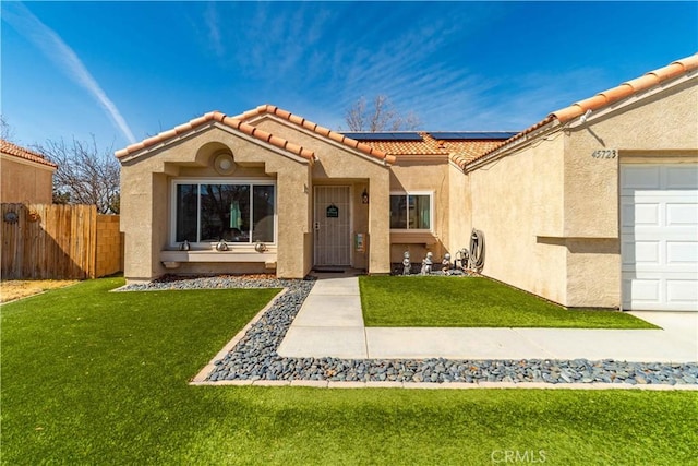 view of front of house featuring stucco siding, roof mounted solar panels, a front lawn, and a tile roof