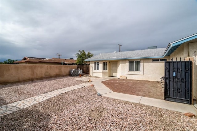 rear view of house featuring a fenced backyard, stucco siding, a shingled roof, and a patio