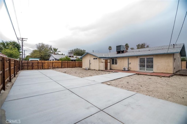 rear view of property with cooling unit, a fenced backyard, stucco siding, and a patio area