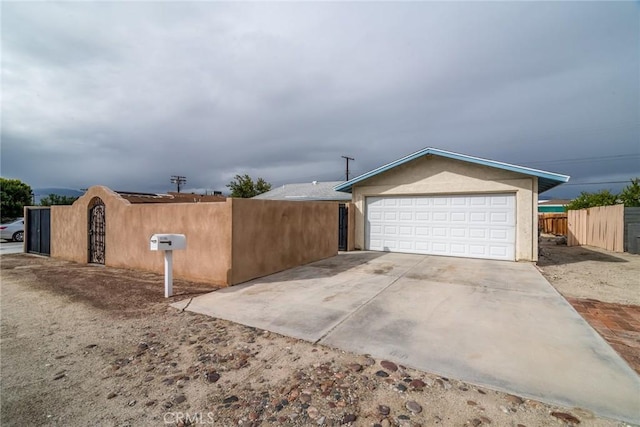 view of property exterior featuring a garage, concrete driveway, stucco siding, and fence