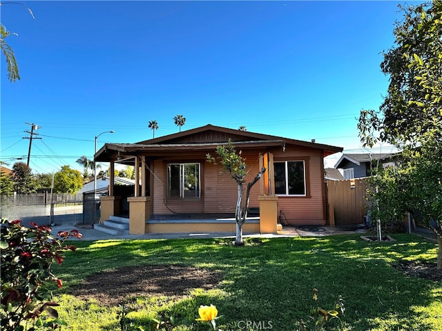 rear view of property featuring a yard and fence