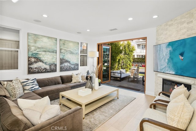 living area featuring visible vents, recessed lighting, a fireplace, and light wood-style floors