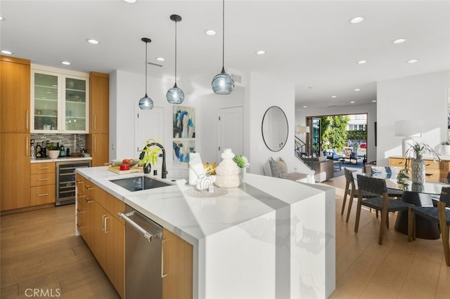 kitchen with a sink, light wood-type flooring, dishwasher, and beverage cooler