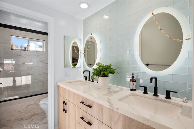 bathroom with double vanity, toilet, marble finish floor, and a sink