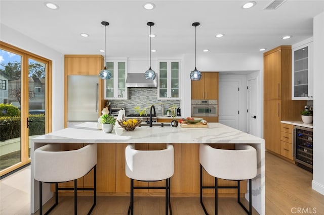 kitchen featuring visible vents, stainless steel appliances, wine cooler, wall chimney range hood, and modern cabinets