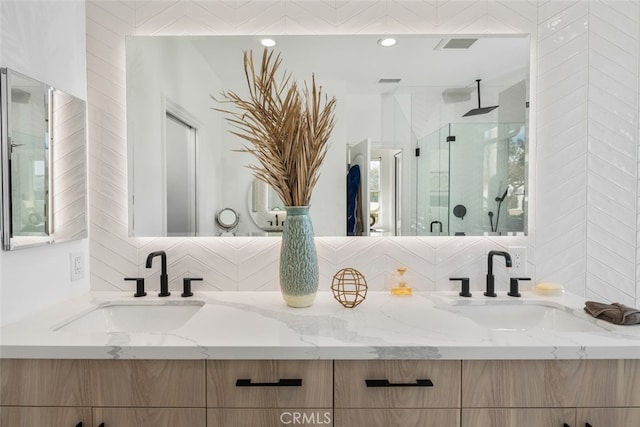 bathroom with a sink, tasteful backsplash, a stall shower, and double vanity