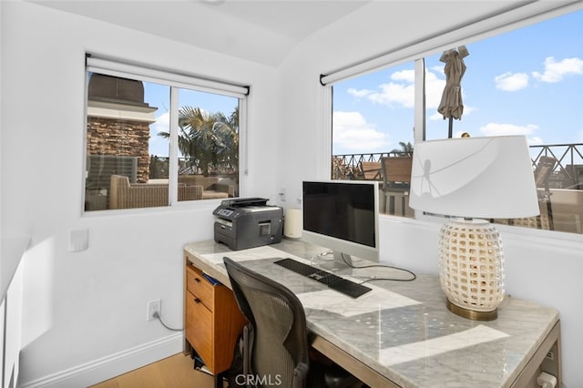 office space with lofted ceiling, light wood-style flooring, plenty of natural light, and baseboards