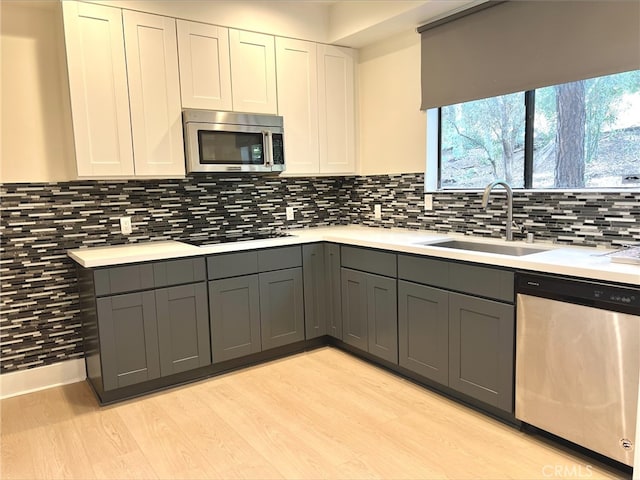 kitchen featuring a sink, light countertops, gray cabinets, and stainless steel appliances